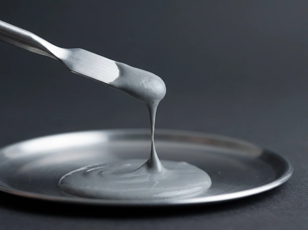 Ceramic slurry lifted by a spatula showing stringing and flow behavior